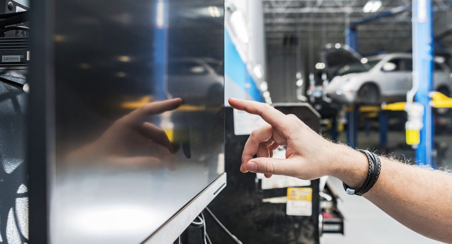 Herr bedient einen Bildschirm in der Fahrzeugfabrik: Effiziente Produktionskontrolle und fortschrittliche Technologie für die Herstellung hochwertiger Fahrzeuge